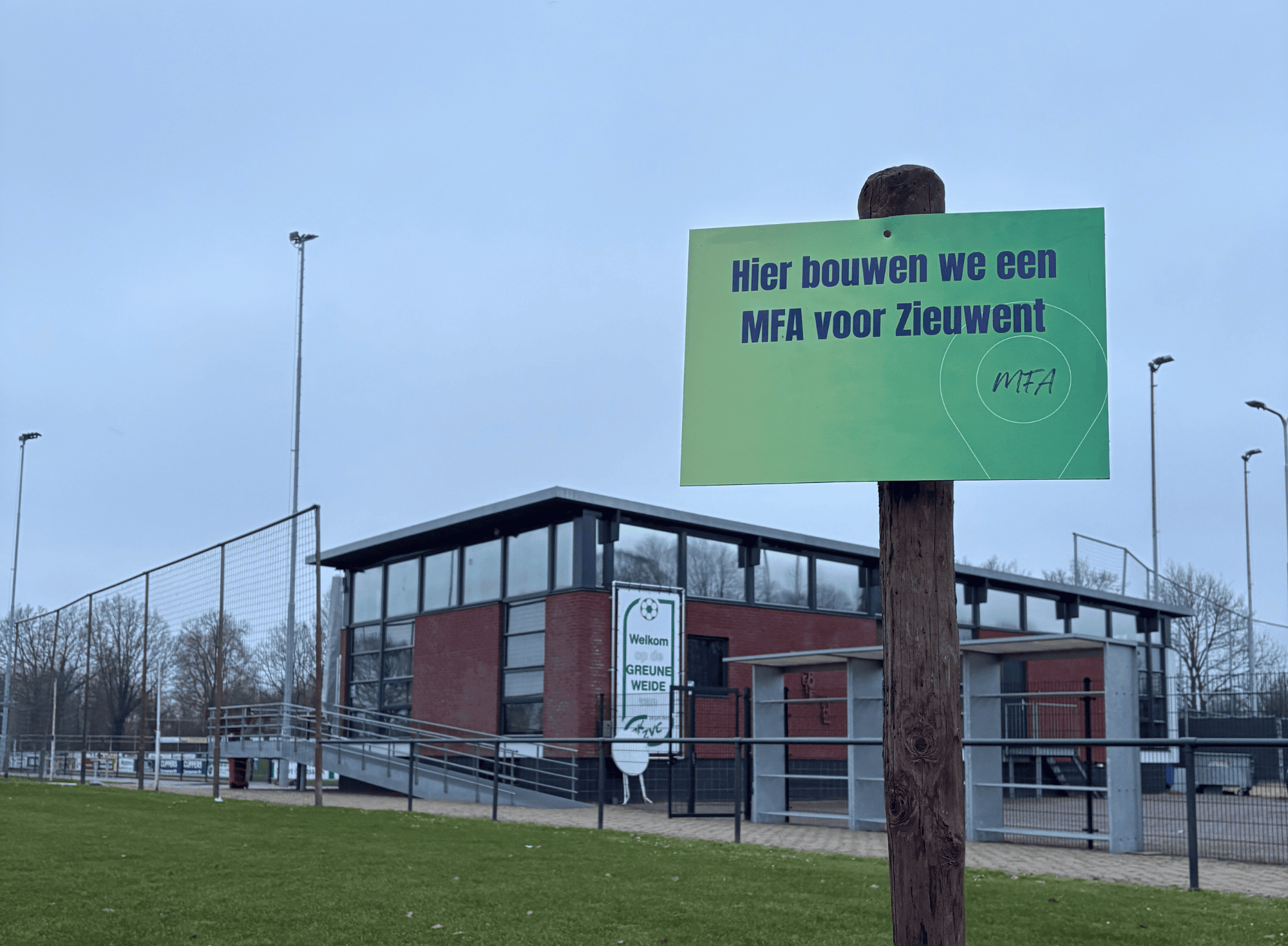 Groene weide met bouwbord voor MFA in Zieuwent, lokale sport en gemeenschap.